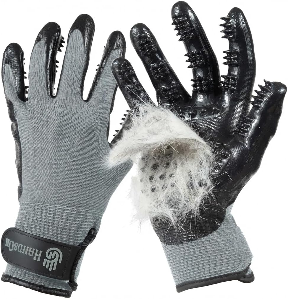 A pair of gray and black pet grooming gloves with spiky fingers, shown on a white background. One glove is turned inside out to demonstrate the grooming surface, with a clump of white pet fur visible on the black palm side.