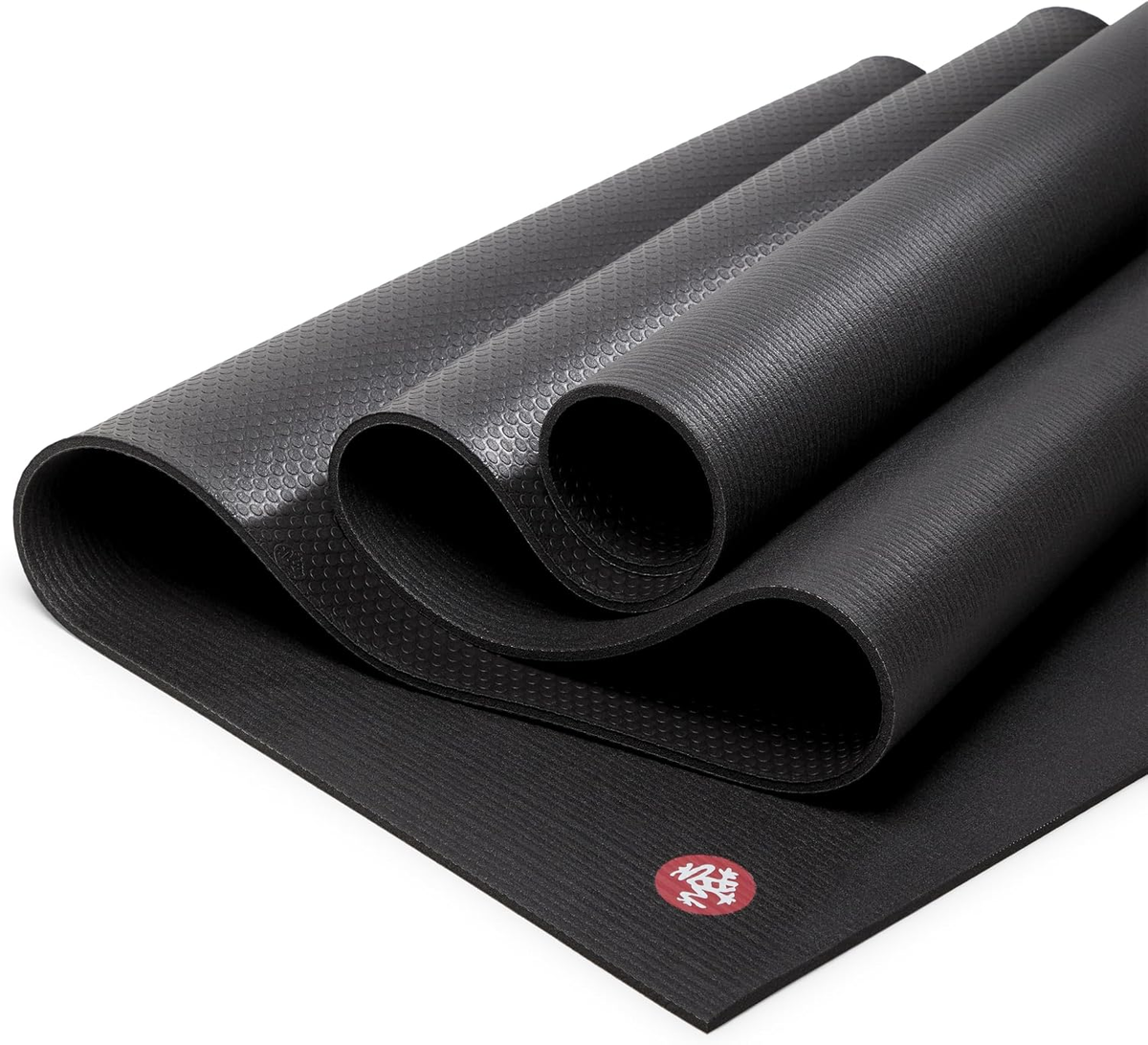 Manduka PRO Yoga Mat 6mm in Black — rolled and folded showing honeycomb grip texture on white background
