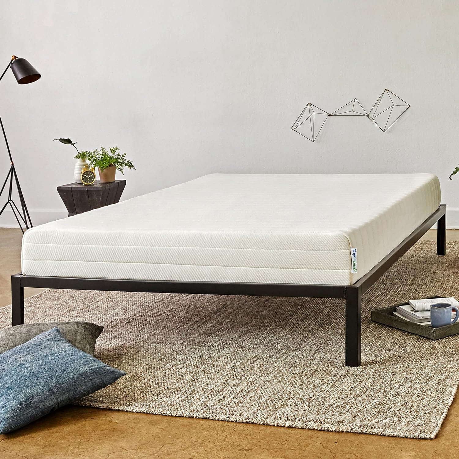 Mattress on a metal frame in a room with decor elements.